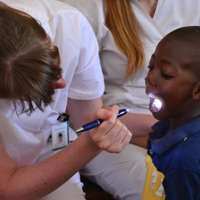 Projects Abroad medical intern examines a young boy's mouth with a pen torch at an outreach programme in Jamaica. Female medical intern examines a young boy's mouth in a care centre during a medical internship in Jamaica.